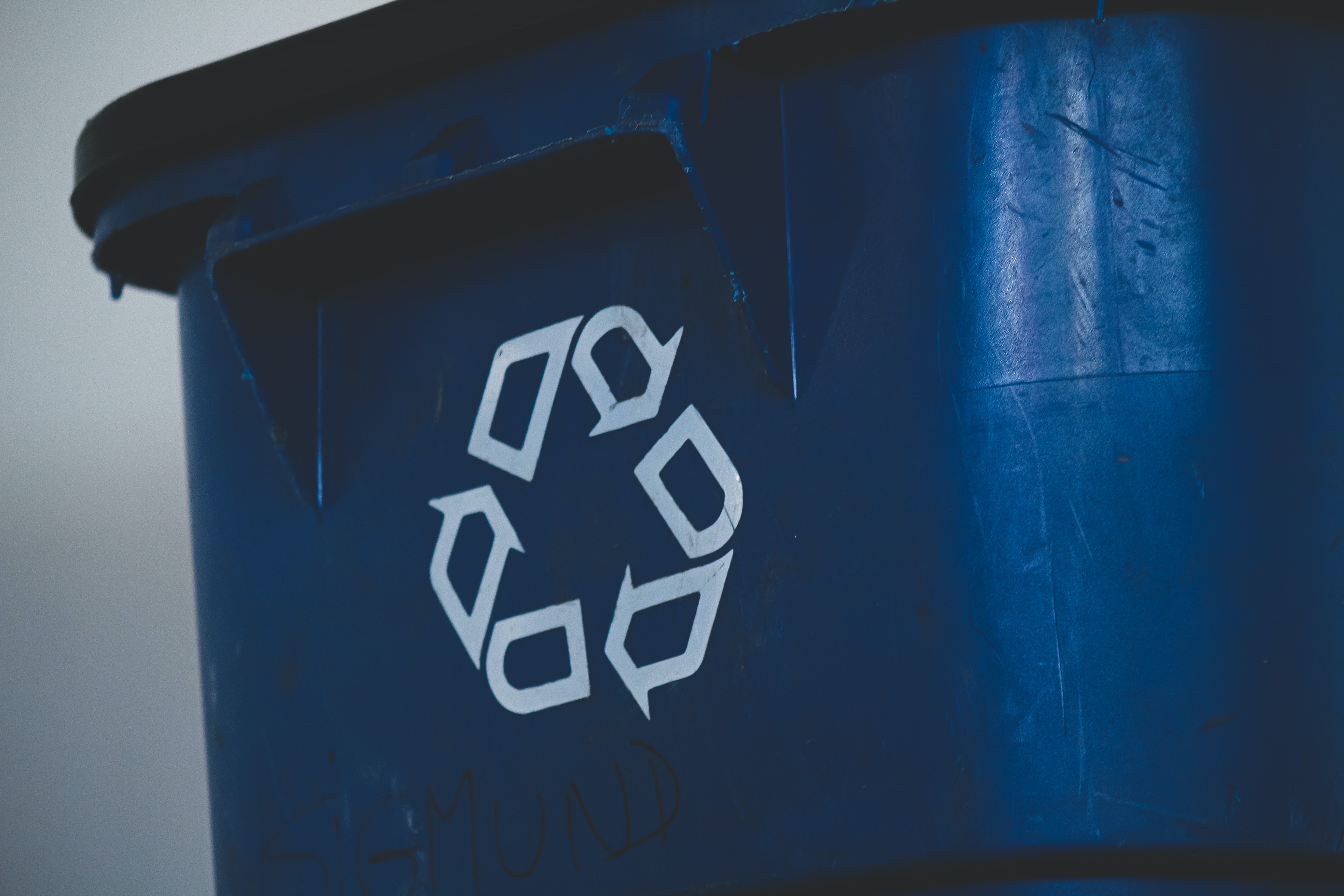 A blue recycling bin with the chasing arrows recycling symbol