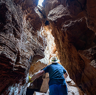 A man walking through Palo Duro Canyon, surrounded by steep canyon walls.