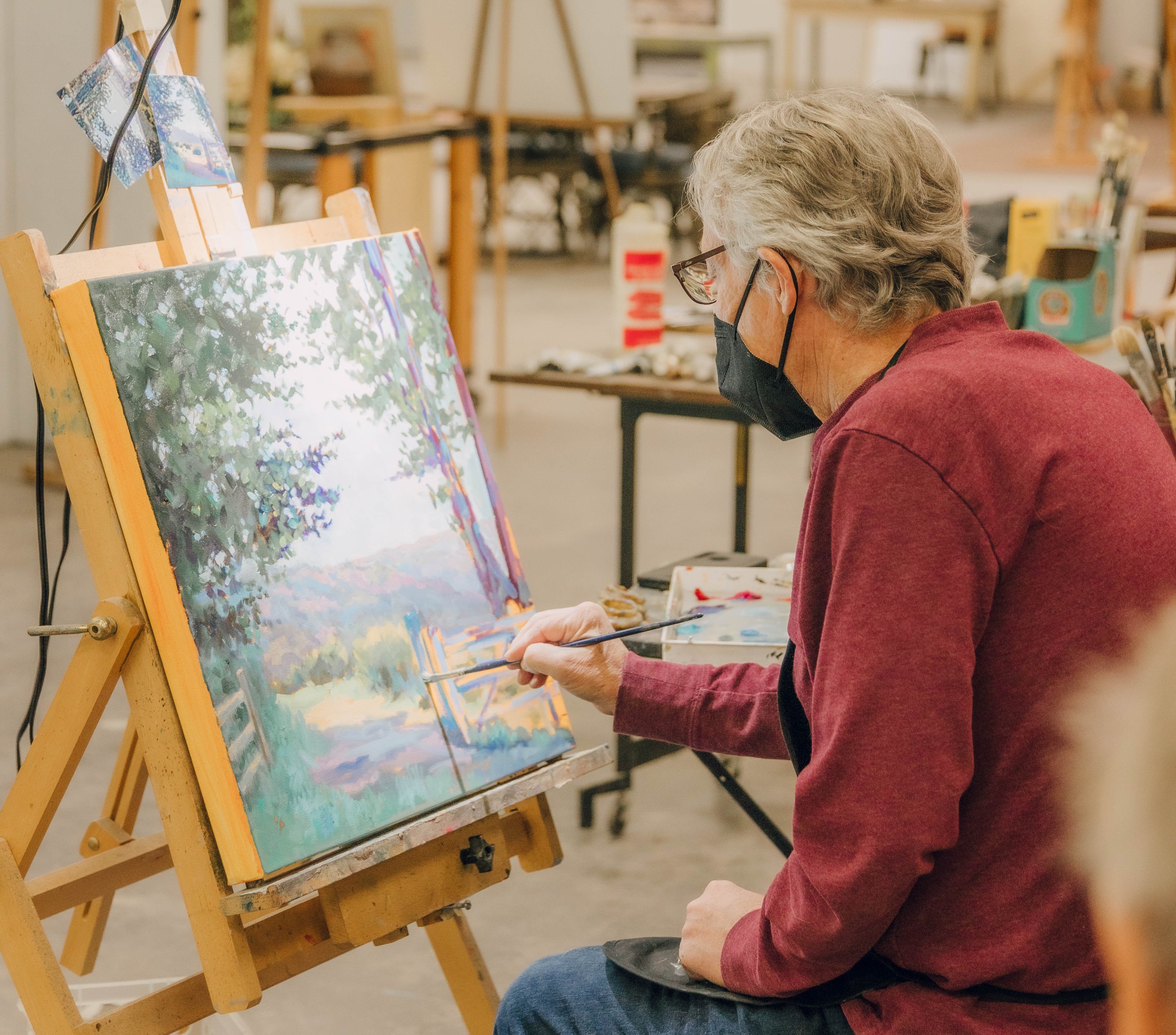 Local artist painting a landscape at easel. 